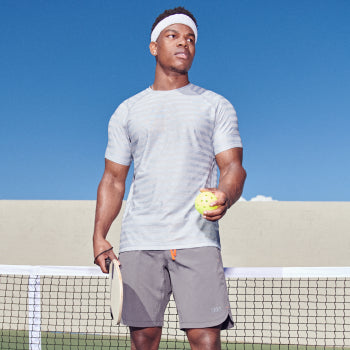 Man at a pickleball court wearing a gray sport tee and training shorts