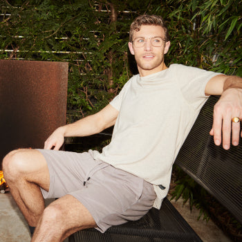Man on a patio bench wearing beige lounge tee and shorts