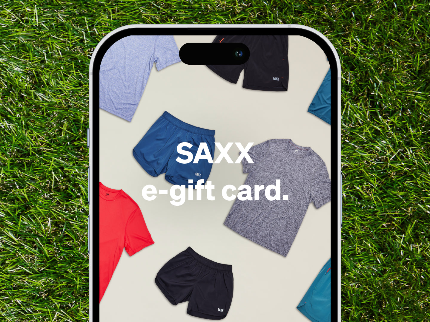 The top half of a smartphone laid on grass. The screen reads "SAXX e-gift card".
