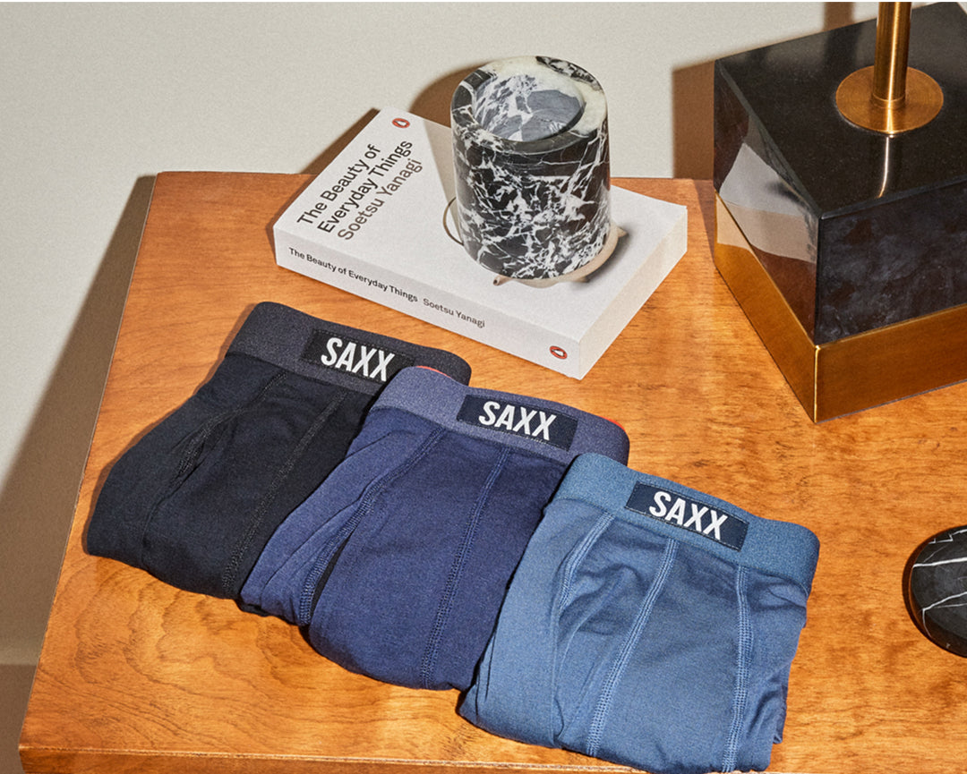Three pairs of SAXX Underwear neatly folded on a wooden table