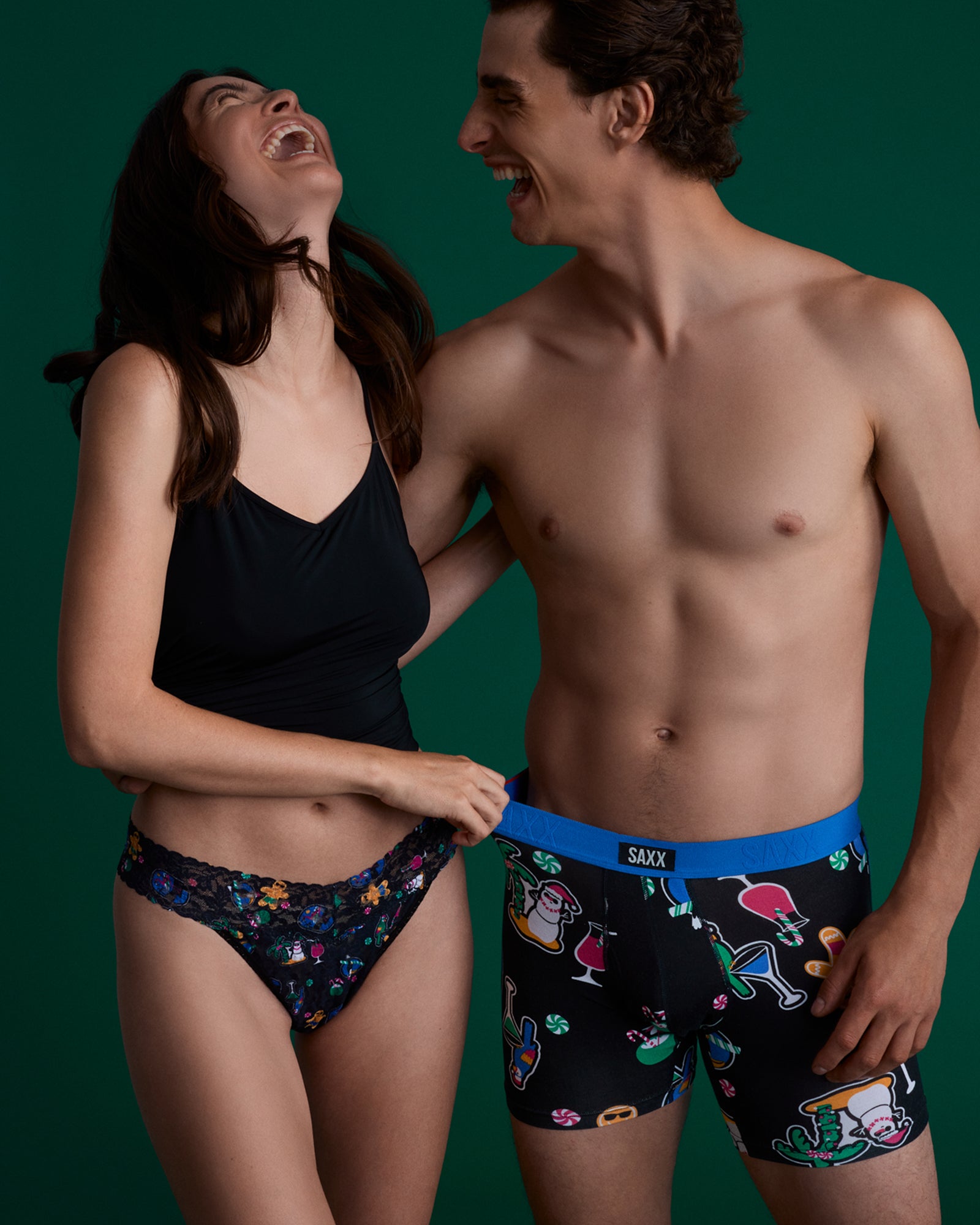 Two people wearing colorful underwear against a green background