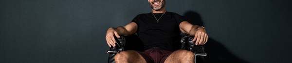 Man in black shirt and red underwear sitting in chair