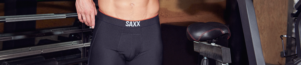 Shirtless man in black underwear standing by stationary bike