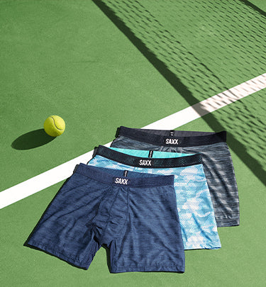 Three pairs of blue DropTemp Cooling Mesh Boxer Briefs lying on top of each other on a tennis court