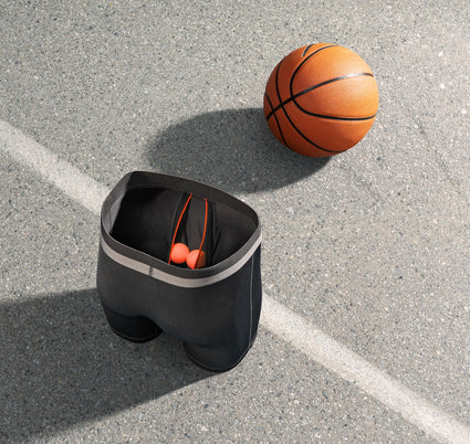 SAXX Boxer Briefs with two orange ping pong balls in the BallPark Pouch next to a basketball on a basketball court