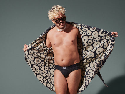 A person holding open their robe to showcase their black SAXX Underwear briefs underneath