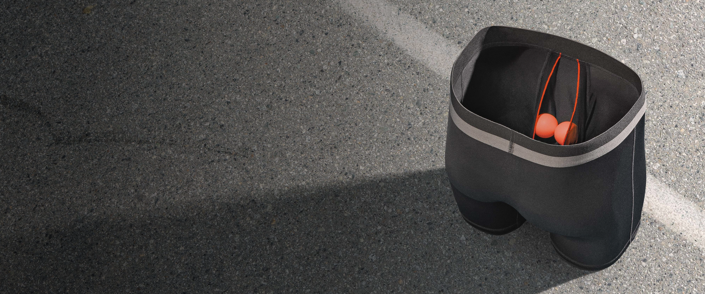 A pair of Grey Boxer Briefs propped up, with two orange balls sitting comfortably in the BallPark Pouch™