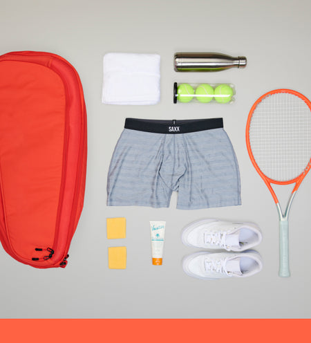 Grey boxer brief surrounded by tennis equipment such as racket balls and bag