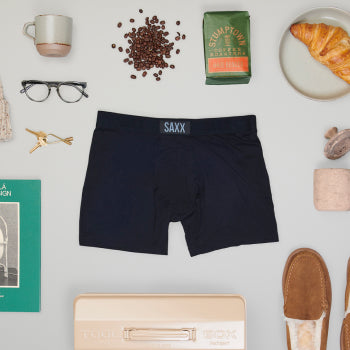 Black pair of boxer briefs surrounded by household items such as coffee beans and keys