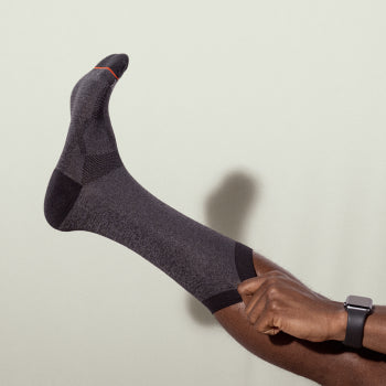 Man pulling gray and black socks up the leg