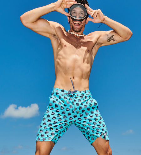 Shirtless man in blue swim shorts and goggles jumping