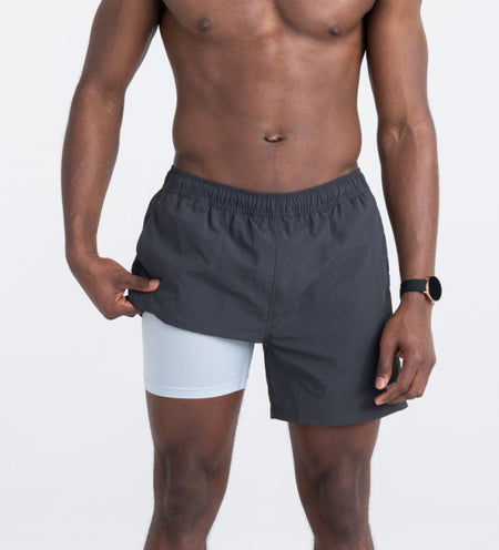 Man wearing dark gray swim shorts while holding up the leg to show liner