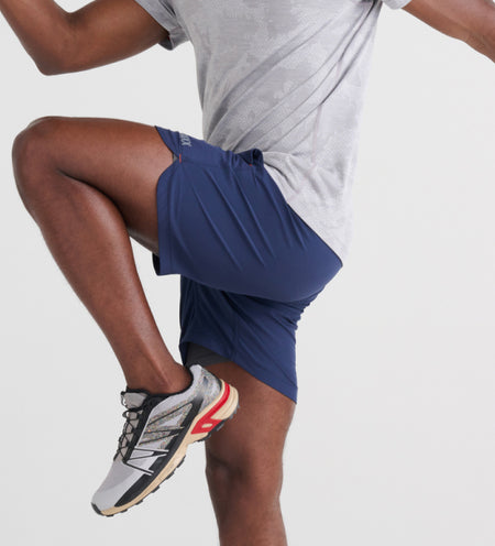 Man doing knee highs in navy blue 2N1 Shorts and gray runners