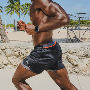 Shirtless man running in black athletic shorts and shoes