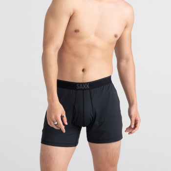 Shirtless man standing in black loose fit boxers
