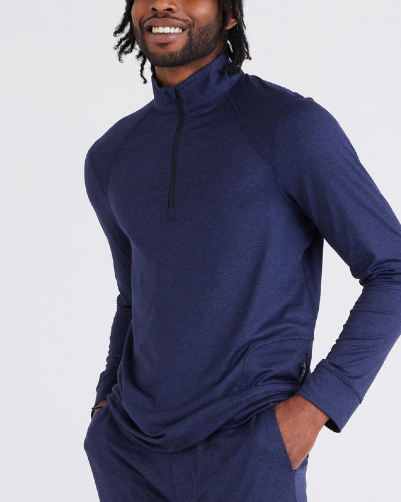 A man seen from the chin to hip. He wears a blue half-zip, funnel-neck sweatshirt. He's chest faces the left side of the image.