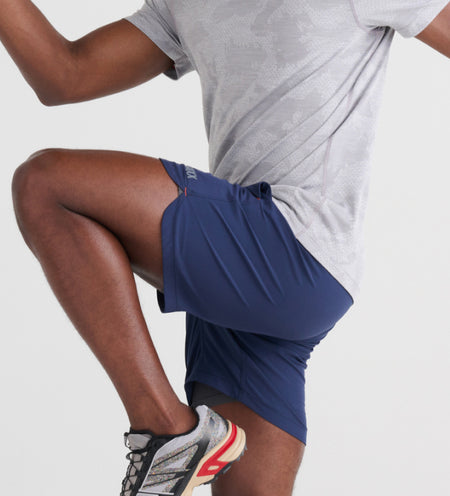 Man wearing a light gray tee and blue 2N1 Shorts while doing knee highs