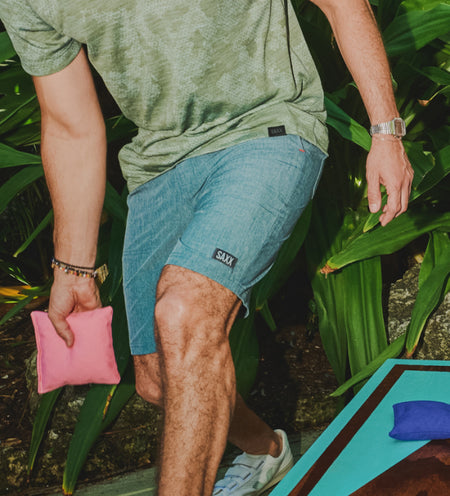 Man wearing green active shirt and blue 2N1 Shorts while playing cornhole