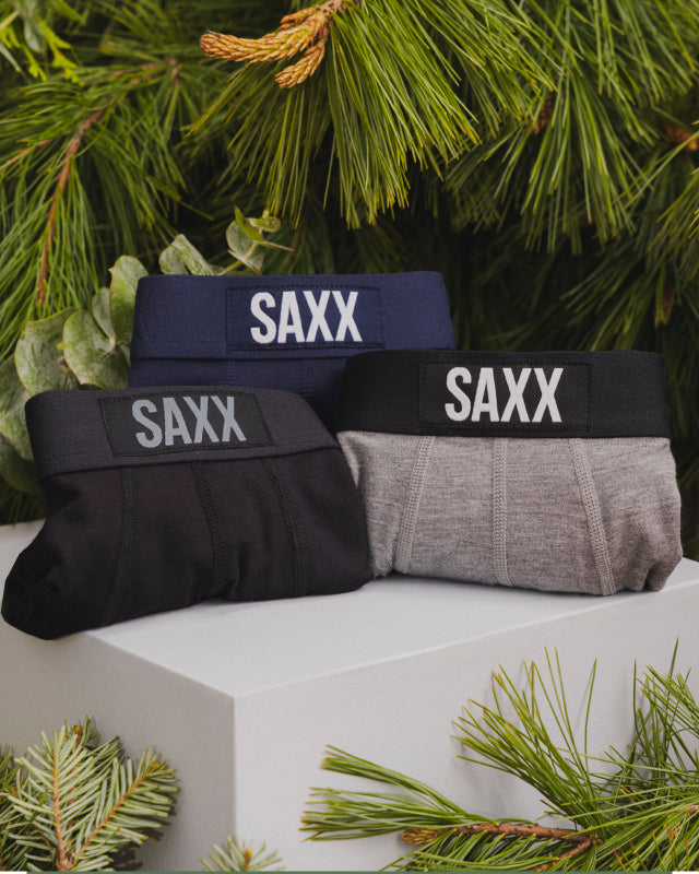 Three pairs of underwear on a white box. One is black. One is blue. One is grey.