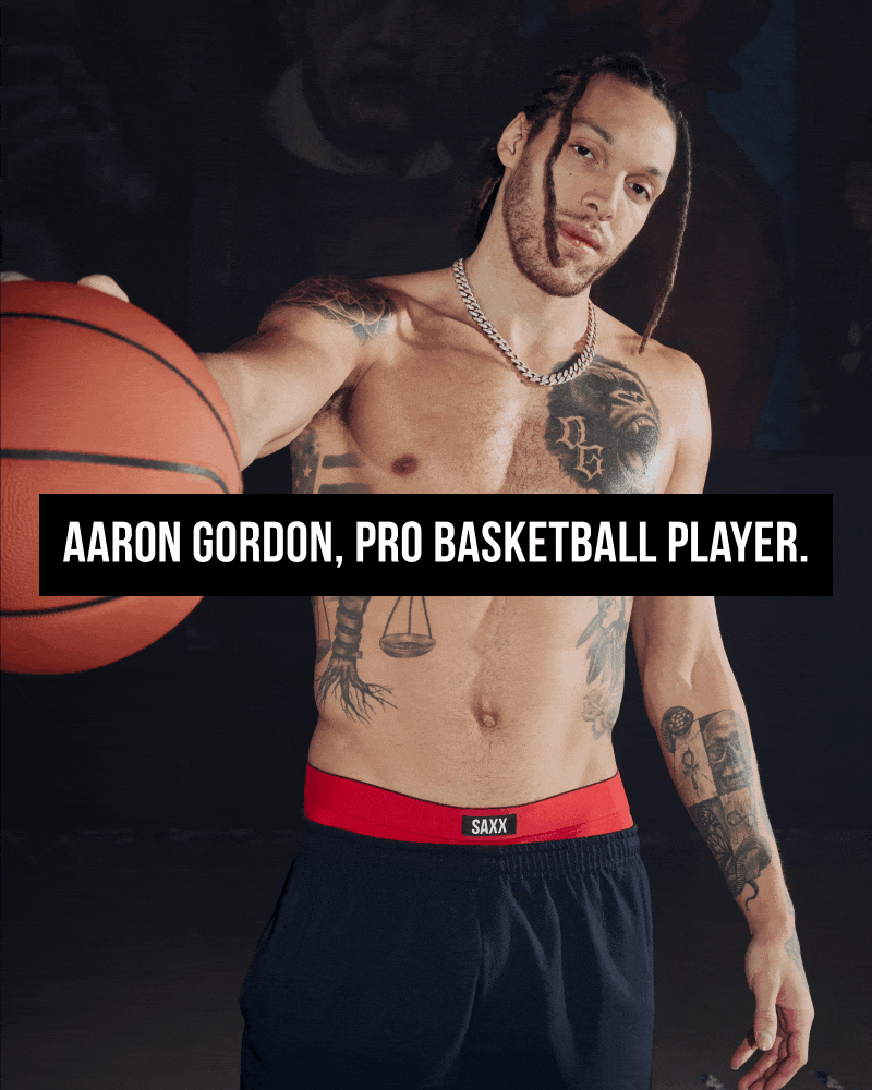 A gif of a man wearing boxer briefs and holding a basketball toward the camera. 