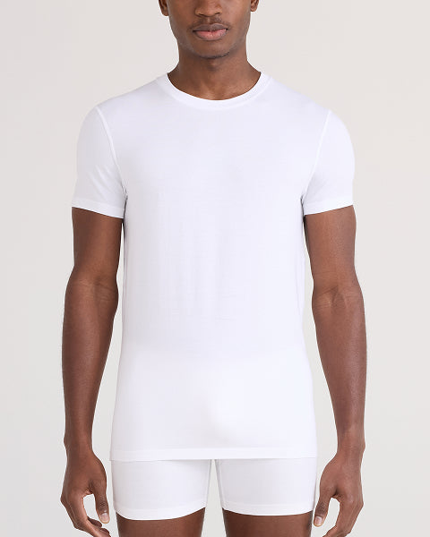 Man wearing a plain white t-shirt and shorts on a light background