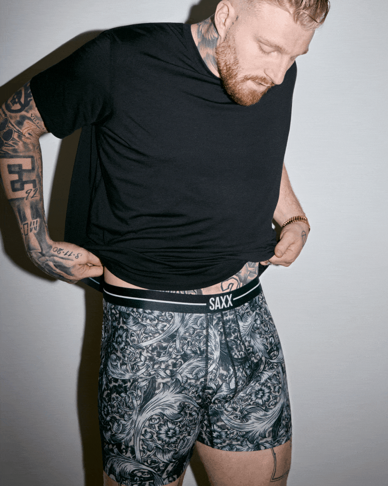A gif. First frame a man wearing a black t-shirt and grey print underwear. Second frame a close up of grey print.