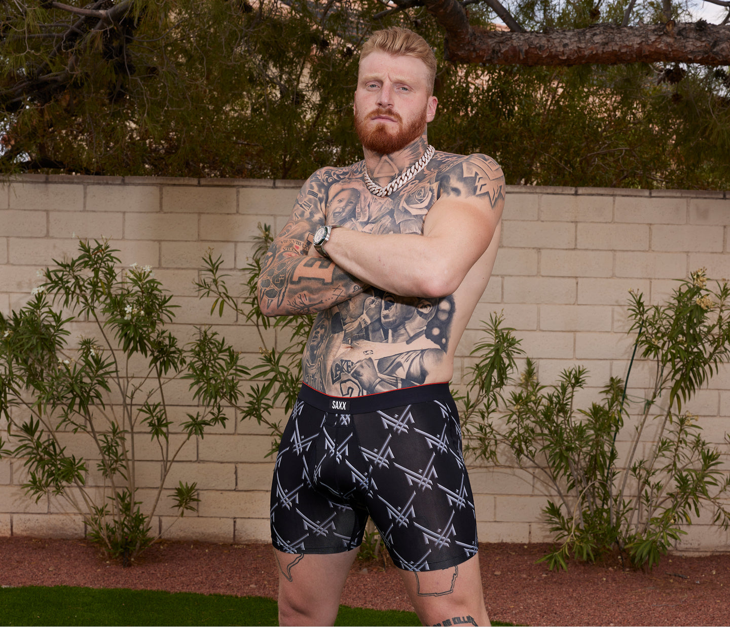 Pro Football Player and SAXX Gamechanger Maxx Crosby wearing black shorts with white patterns in an outdoor setting.