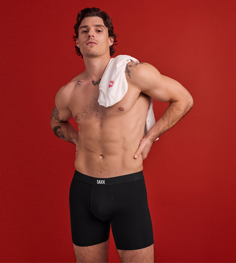 Man wearing black SAXX underwear with a red background