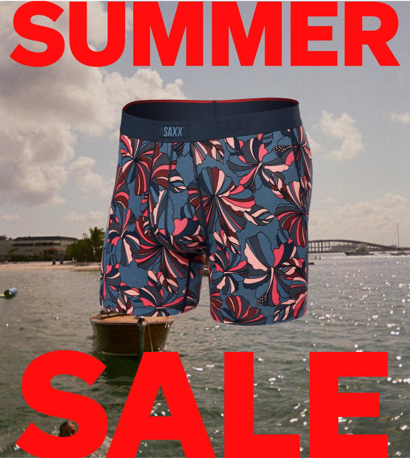Floral-patterned boxer briefs with 'SAXX' branding on a beach background with 'SUMMER SALE' text.