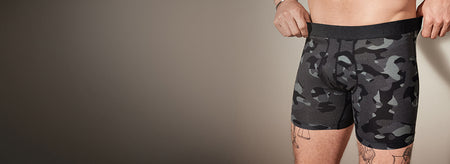 Person wearing camouflage boxer briefs against a neutral background