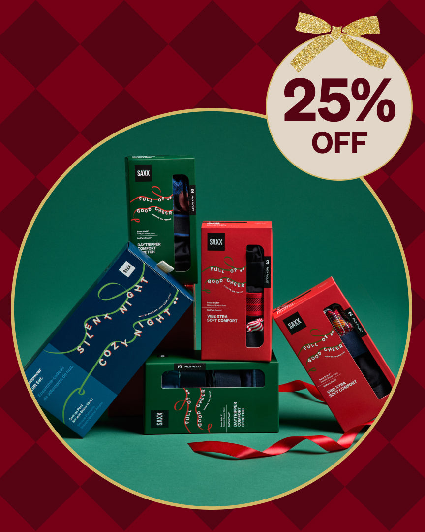 Mens holiday gift boxes displayed on a festive surface showing a limited time 25 percent savings on SAXX seasonal holiday gift box styles