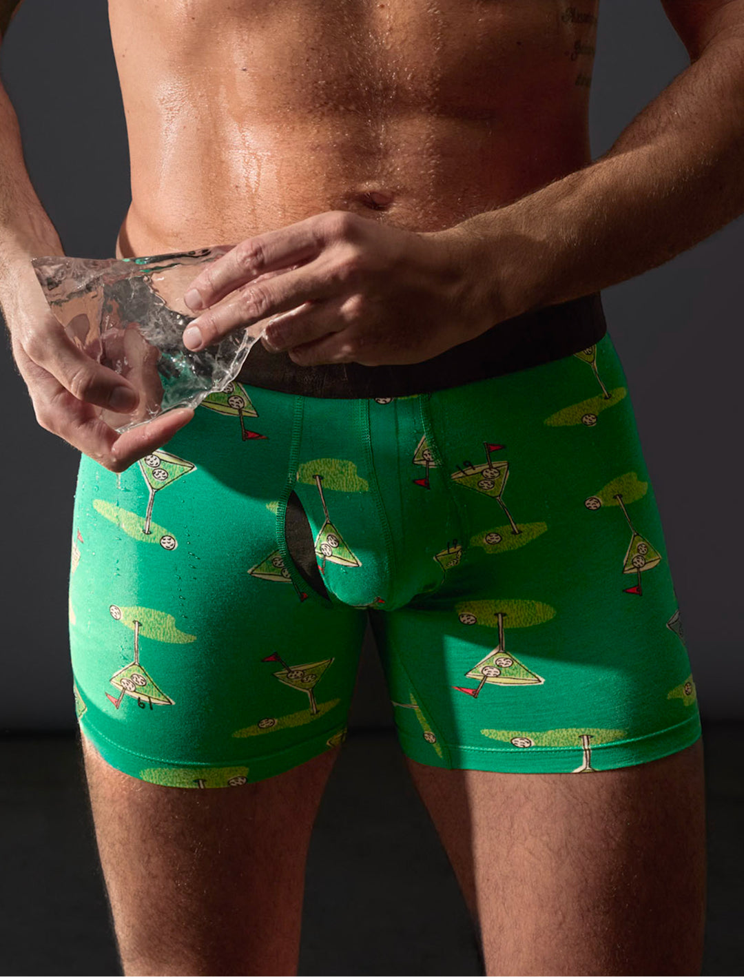 Person wearing green boxer briefs with a pattern, holding a clear bag.