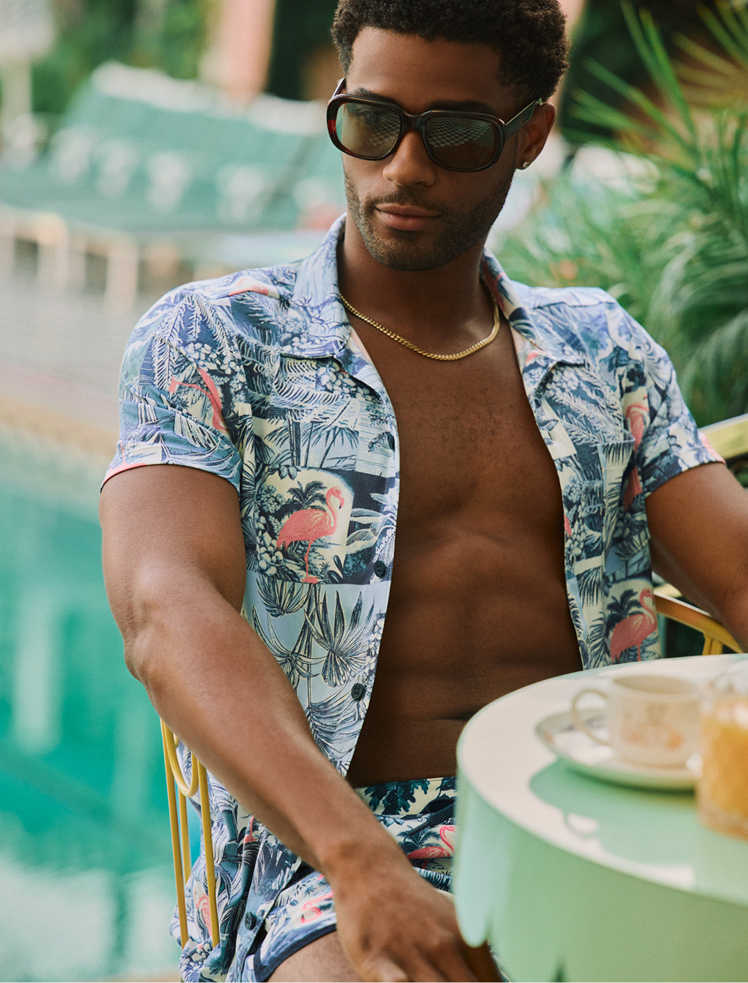 Man wearing a colorful Hawaiian shirt sitting outdoors with plants in the background