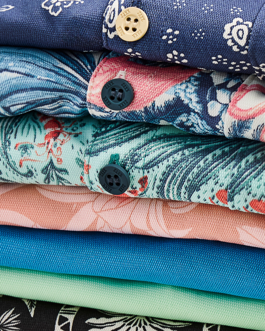 Stack of colorful patterned fabrics with buttons on a white background
