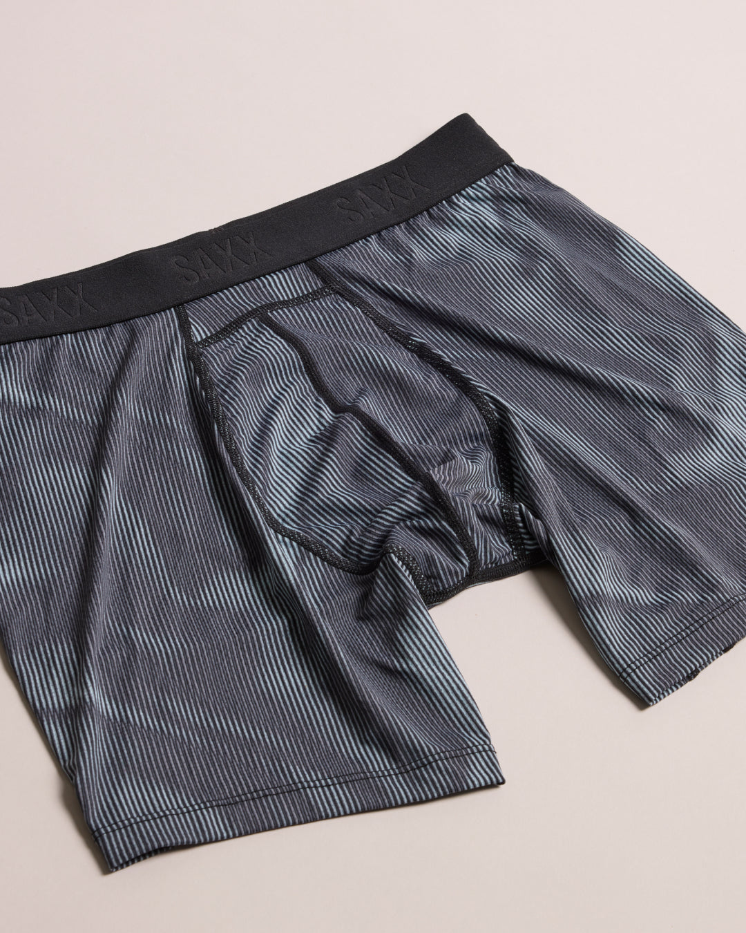 Gray boxer briefs with a black waistband on a beige background