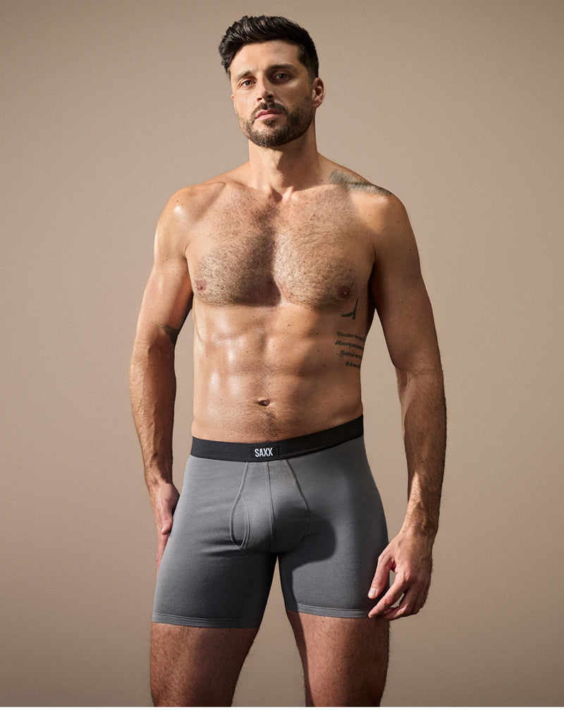 A shirtless man posing in grey SAXX Underwear Boxer Briefs