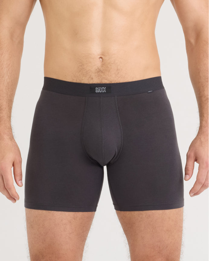 A close-up of a man's lower torso wearing dark charcoal gray boxer briefs with a wide elastic waistband and a small white logo on the front.