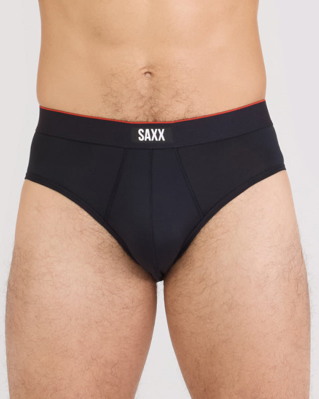 Model wearing black SAXX briefs on a plain background