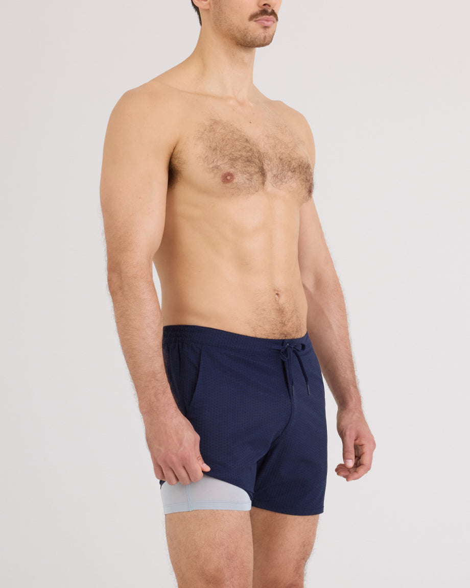Model wearing navy SAXX Harbormaster shorts on a white background