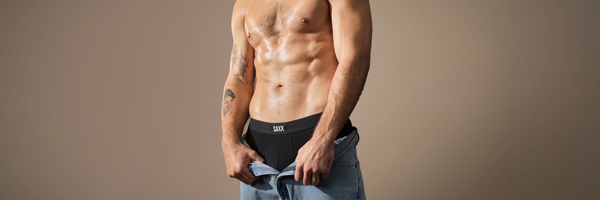 Man wearing black underwear with visible brand logo on a beige background