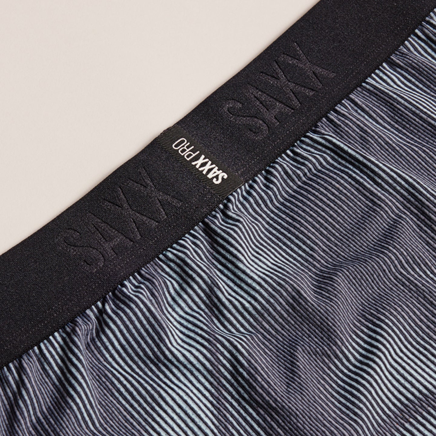 Close-up of black waistband with 'SAXX PRO' branding on gray boxer briefs.