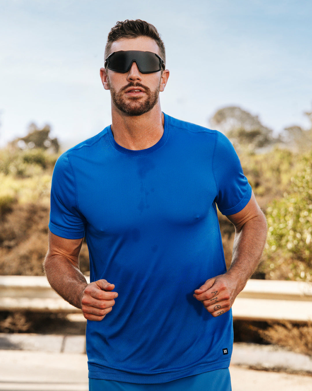 Man wearing a blue athletic outfit with sunglasses outdoors