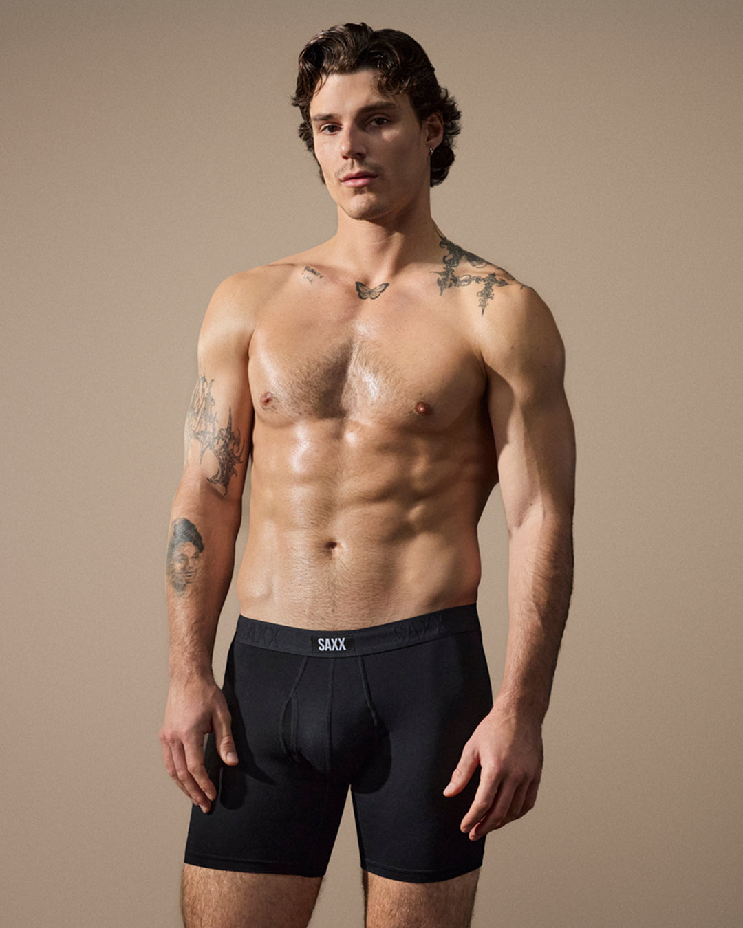 Man wearing black SAXX underwear against a beige background