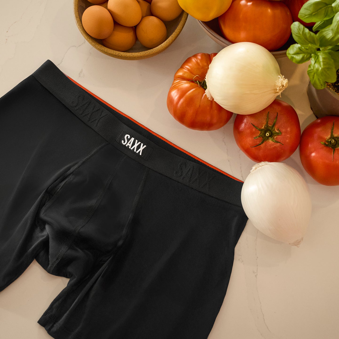 Black SAXX underwear on a table with vegetables and fruits.