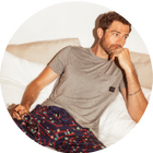 Man wearing gray Sleep tee and pajama pants in a holiday print while laying in bed