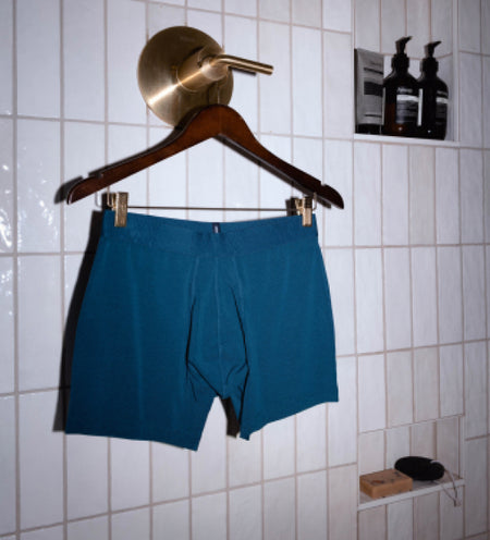 Teal boxer briefs on a hanger hanging off a golden shower valve