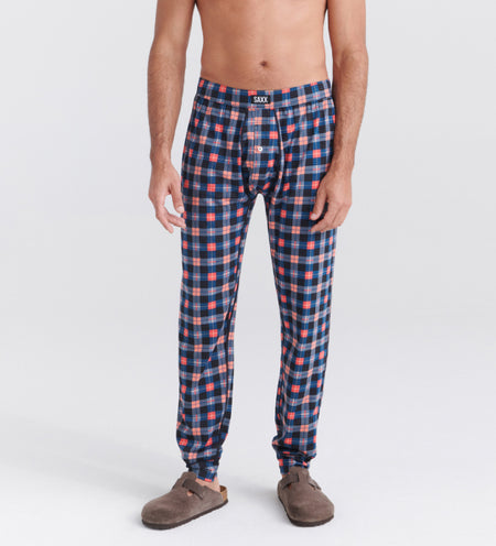 Man wearing cooling sleep pants in a plaid pattern and beige slippers
