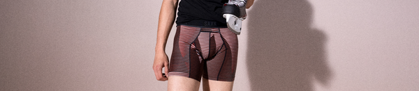 Man in red striped underwear and black shirt holding hockey skate