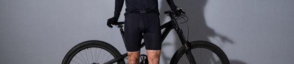 Man in black underwear and shirt leaning on bike