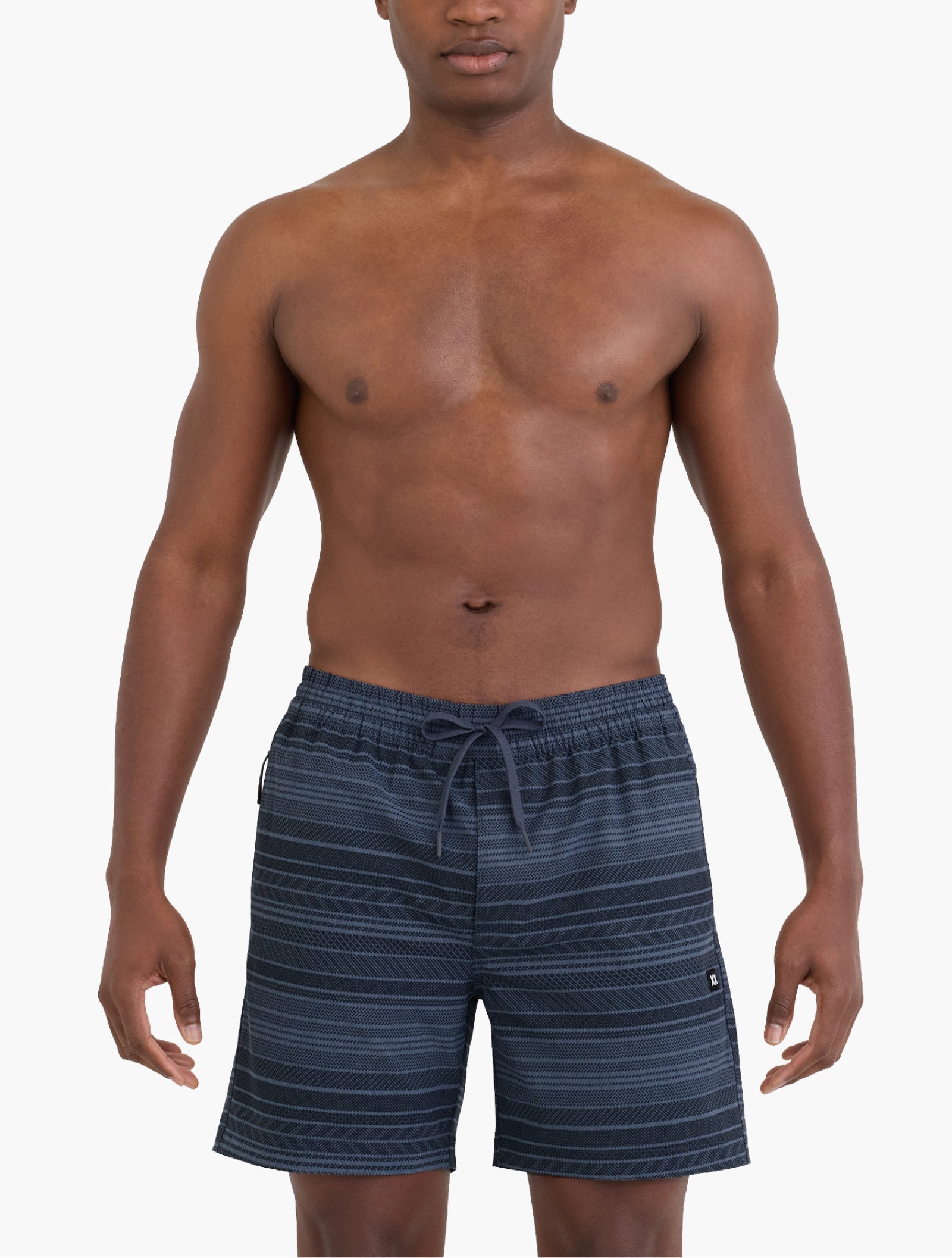Man wearing navy striped swim shorts standing facing forward showing relaxed fit and elastic waistband